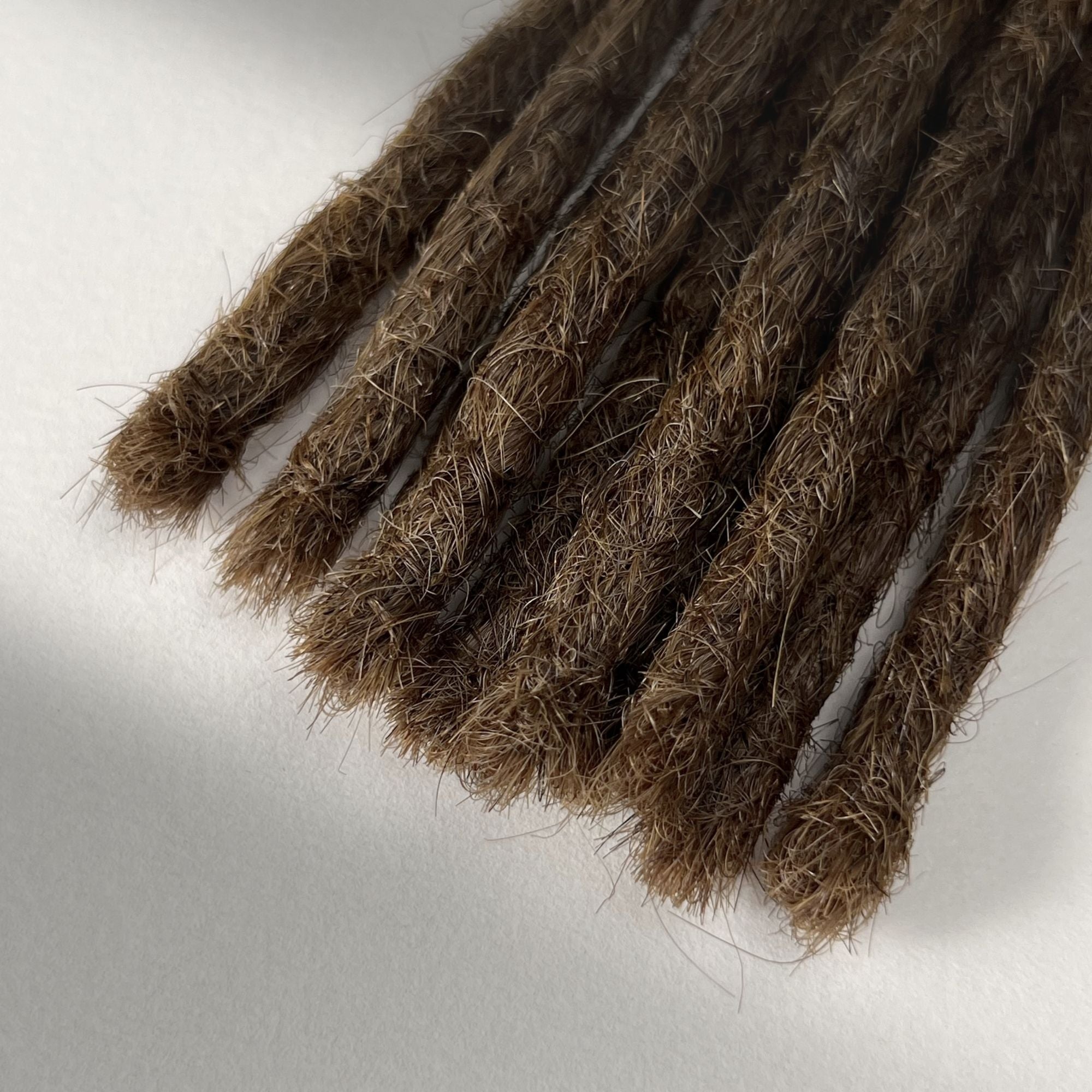 Tip detail of straight loc extensions with blunt ends in Natural Medium Brown.