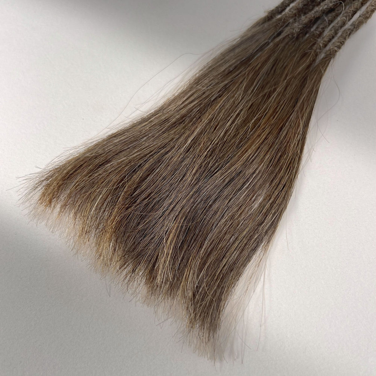 Tip detail of straight loc extensions with long loose ends in Natural Medium Brown.