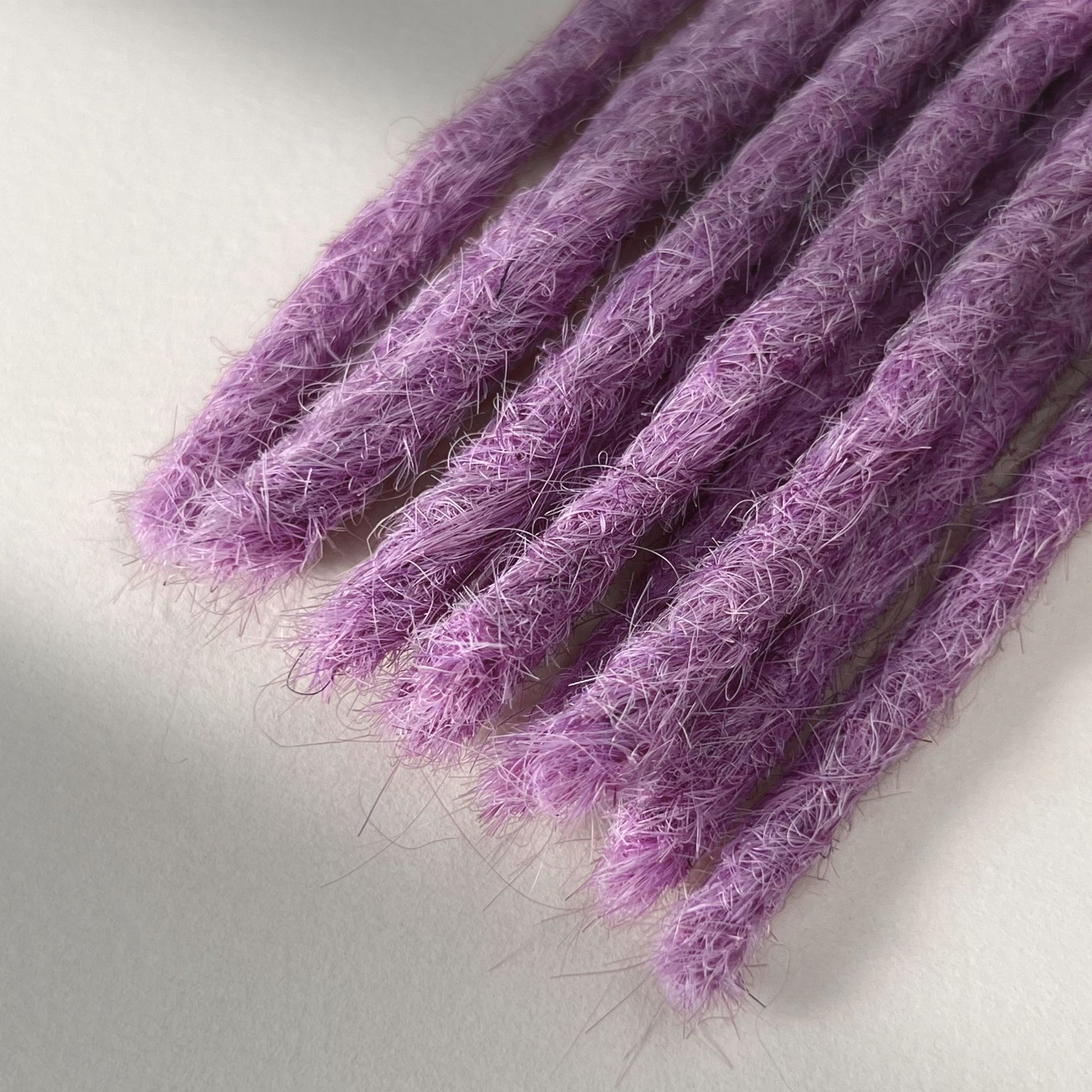 Tip detail of straight loc extensions with blunt ends in Lavender Purple.
