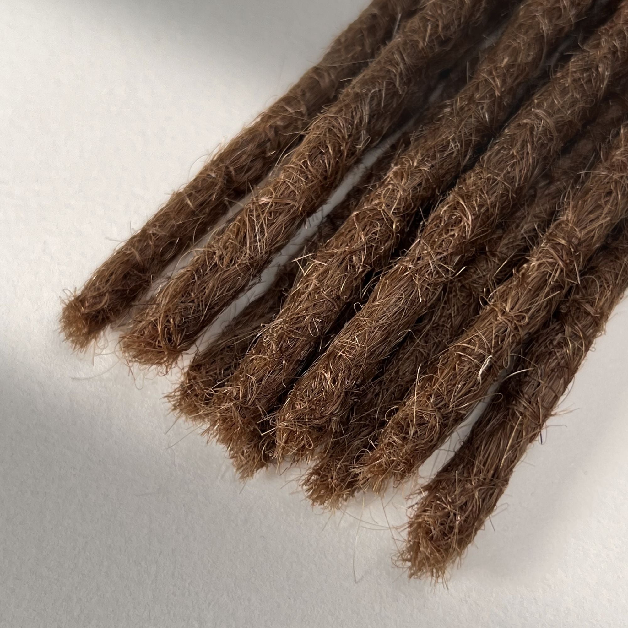 Tip detail of straight loc extensions with blunt ends in Auburn Copper.