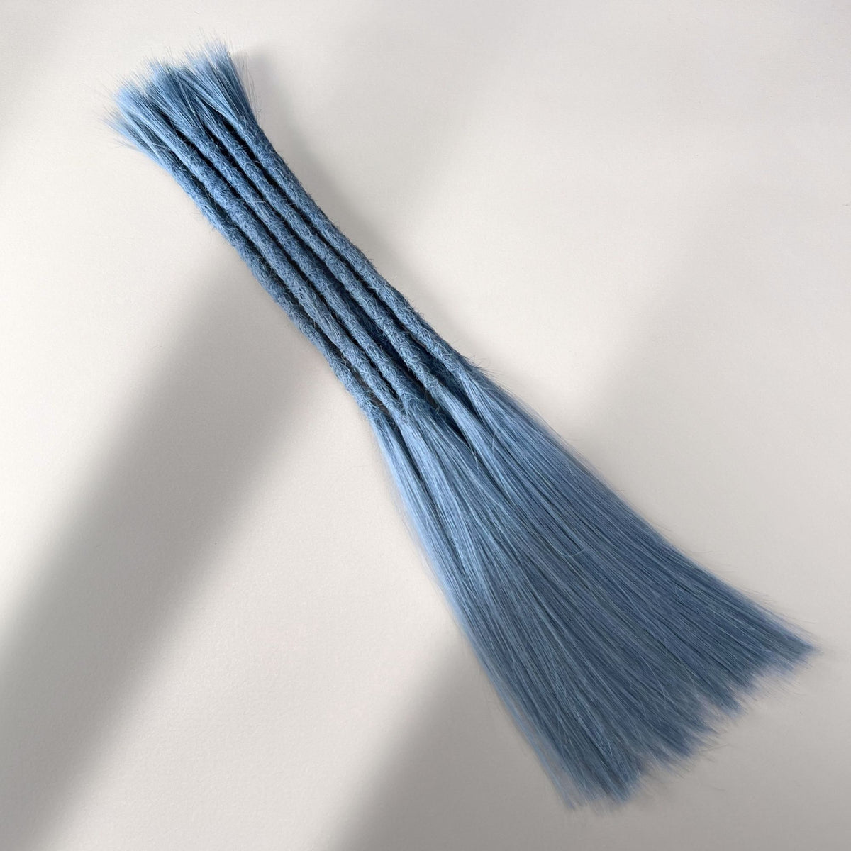 Full view of permanent straight loc extensions with long loose ends in Sky Blue.