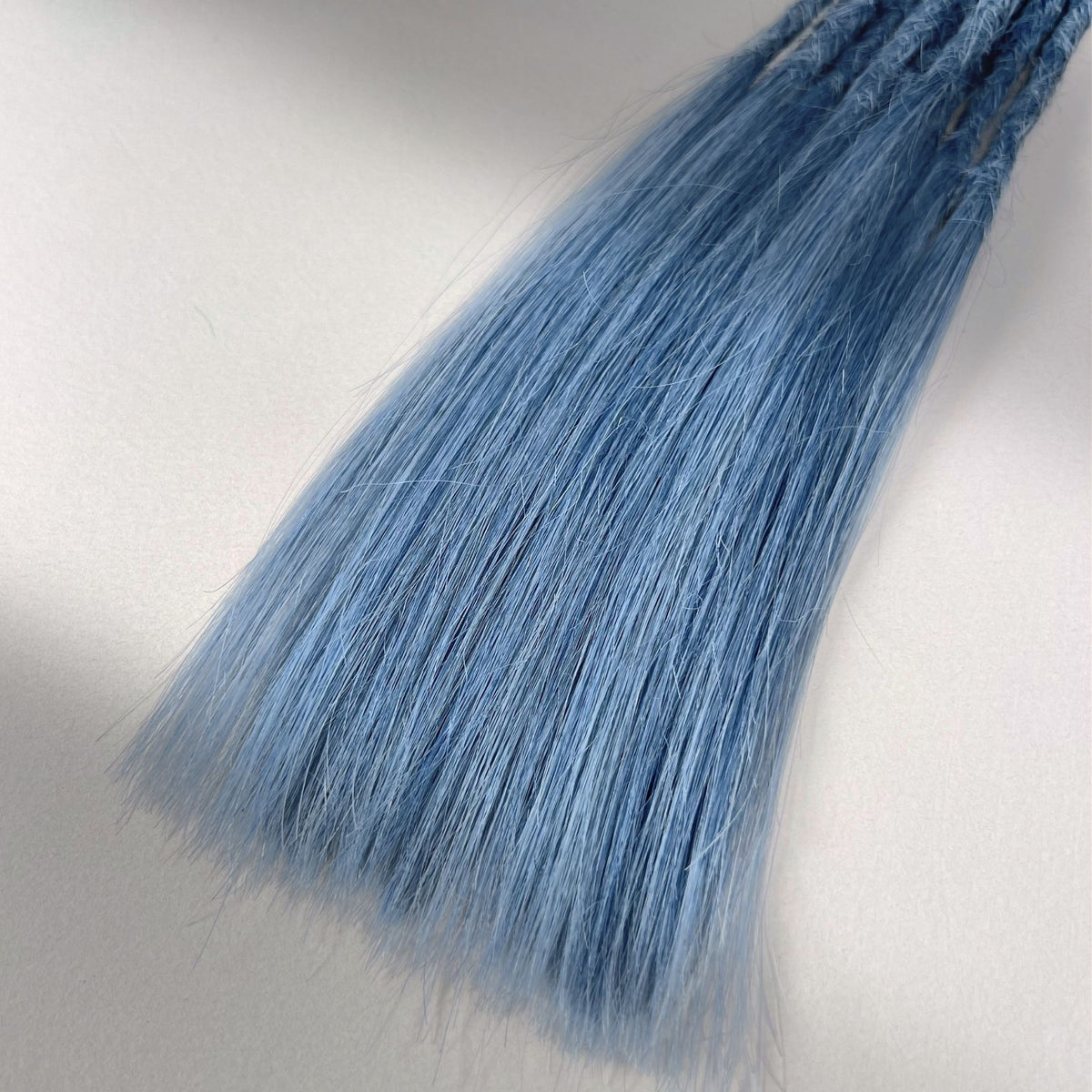 Tip detail of straight loc extensions with long loose ends in Sky Blue.