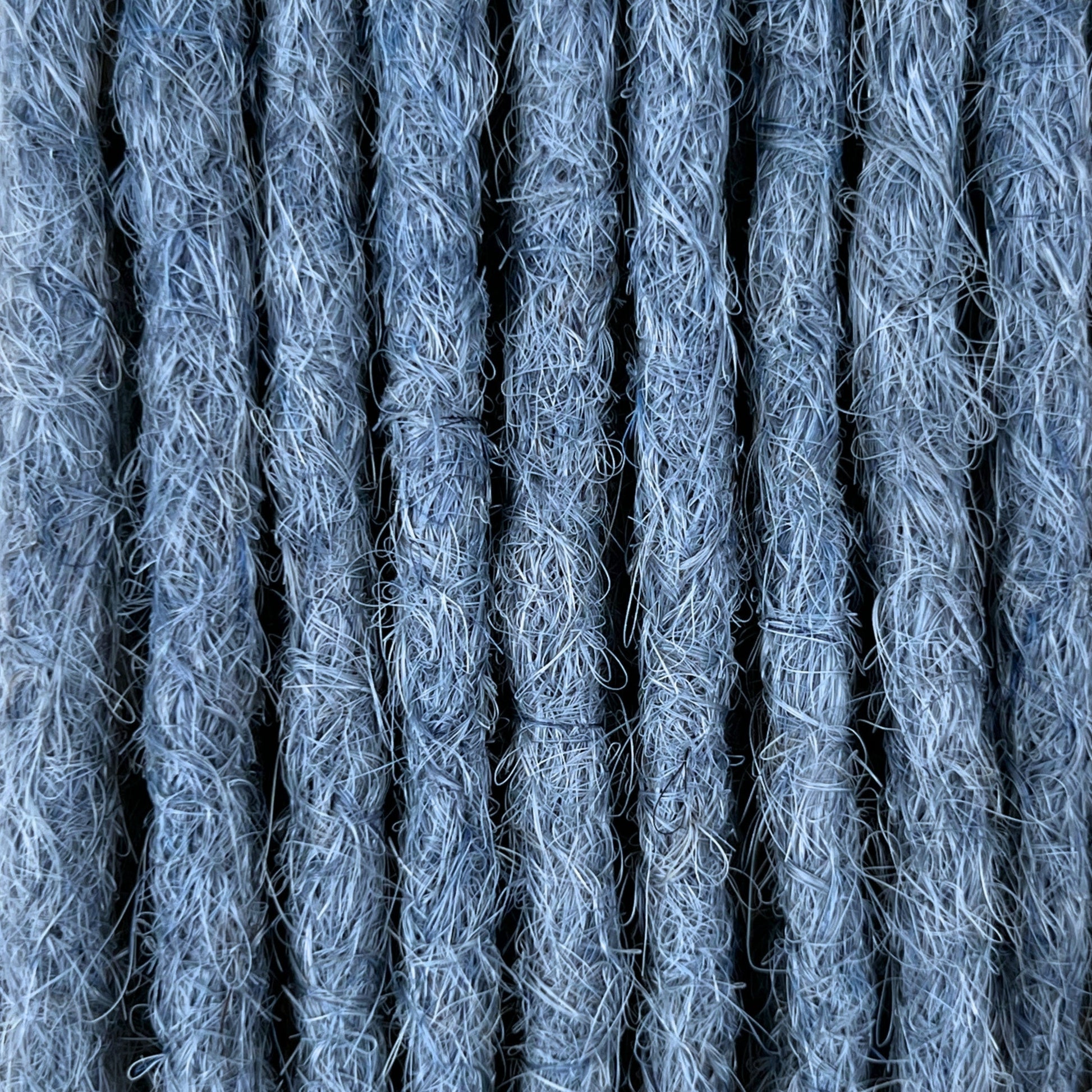 Close-up of straight loc extensions in Sky Blue, showing the texture and color.