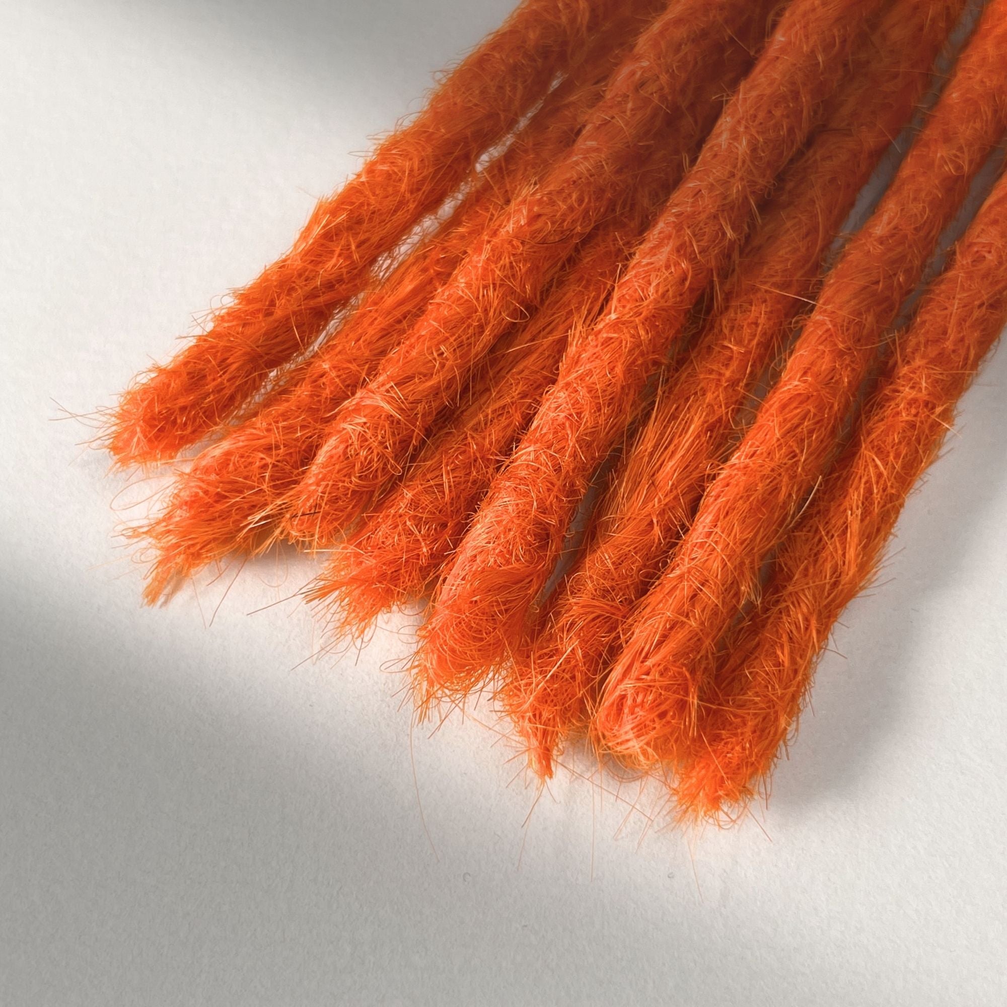Tip detail of straight loc extensions with blunt ends in Burnt Orange.