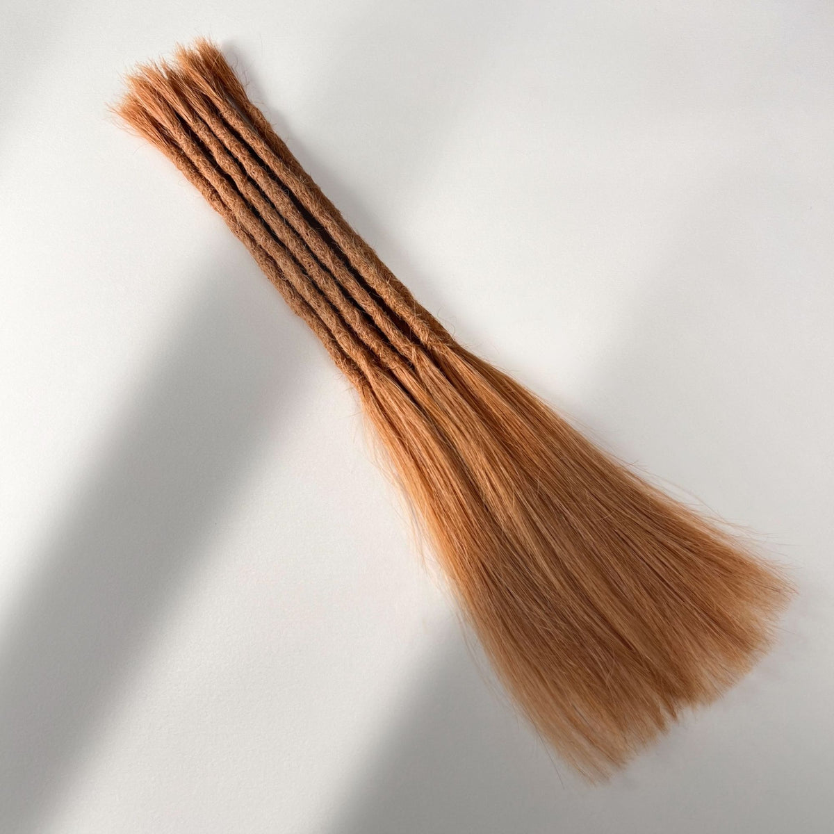 Full view of permanent straight loc extensions with long loose ends in Warm Copper Blonde.