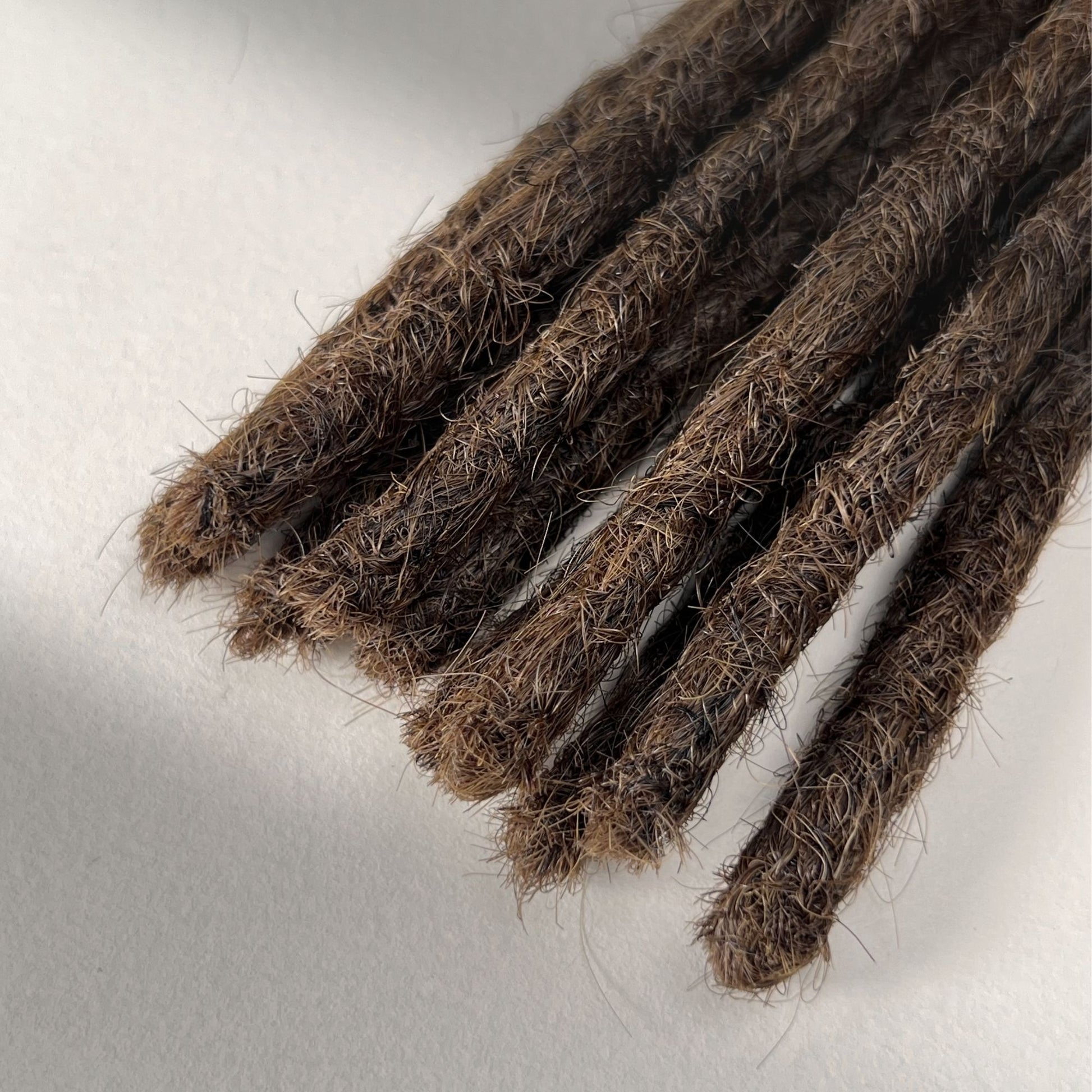 Tip detail of straight loc extensions with blunt ends in Rich Brown.