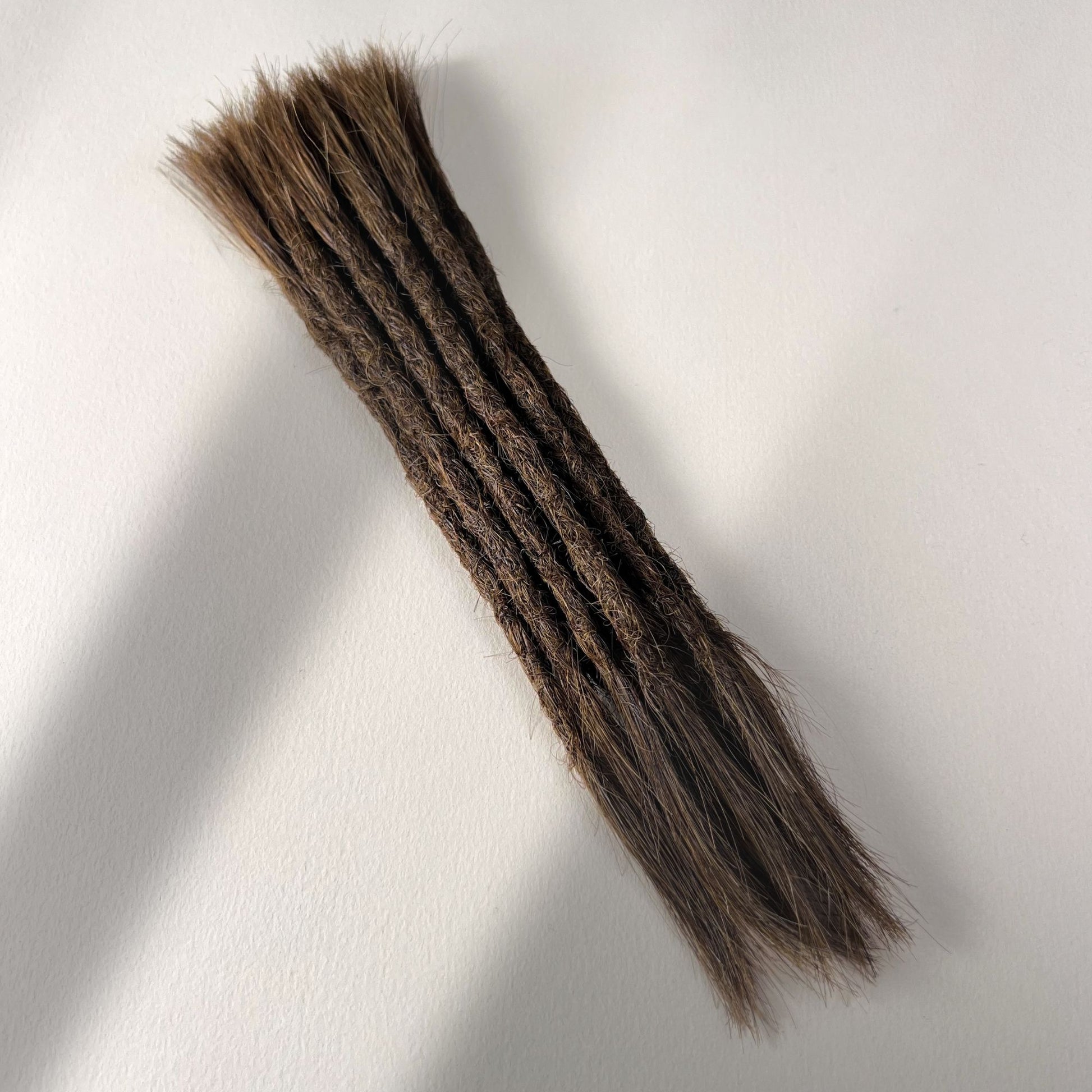 Full view of permanent straight loc extensions with open ends in Rich Brown.