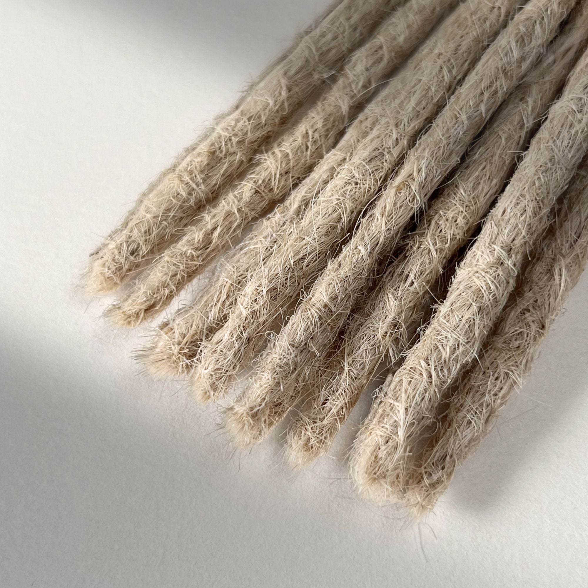 Tip detail of straight loc extensions with blunt ends in Wheat Blonde.