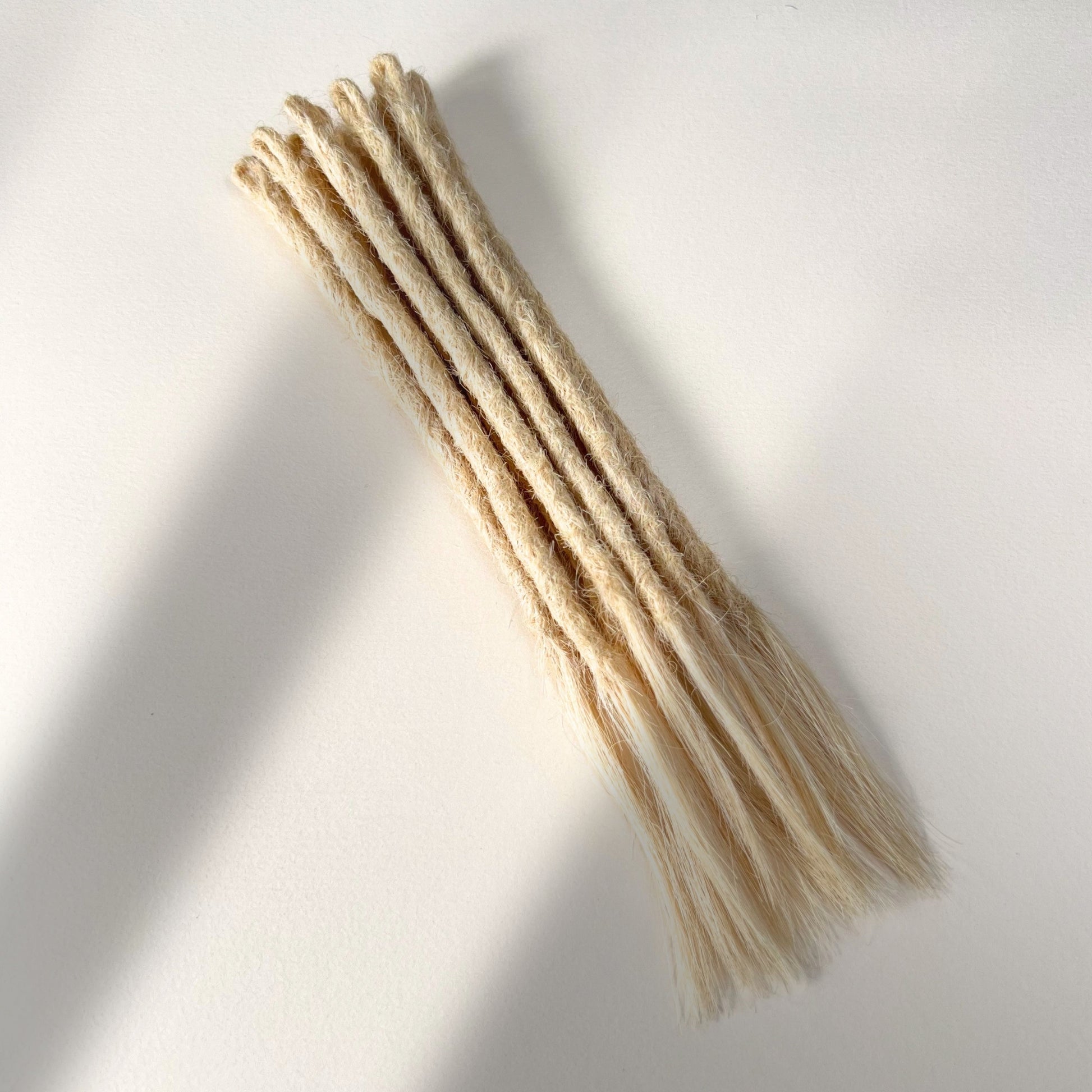 Full view of temporary single-ended straight loc extensions with open ends in Wheat Blonde.