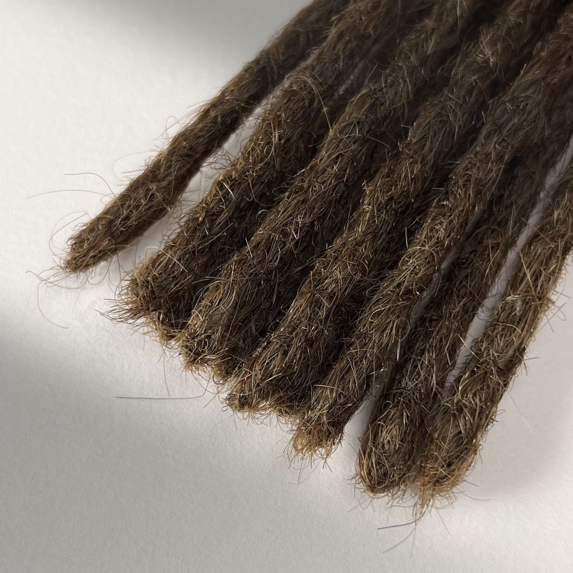 Tip detail of straight loc extensions with blunt ends in Medium Brown.